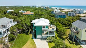 Un quartier résidentiel situé sur la côte, avec des maisons, une plage et une jetée en arrière-plan.