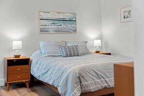 Ein Schlafzimmer mit einem Bett, zwei Nachttischen, einem Wandbild und einer Ablagefläche.