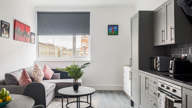 Un appartement moderne comprenant un espace de vie, une cuisine et une grande fenêtre donnant sur la ville.