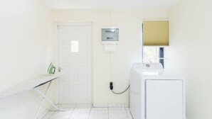 A laundry room with a washing machine, an ironing board, and a door. - Luxury 6BR Villa w/ Private Pool near Palm Beach (Noord)