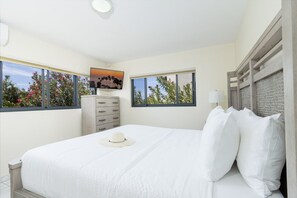 A bedroom with a bed, a dresser, a television, and windows with a view of trees and sky. - Luxury 6BR Villa w/ Private Pool near Palm Beach (Noord)