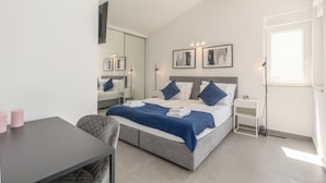 Ein modernes Schlafzimmer mit einem Bett, Nachttischen, einem Schreibtisch und einem Sessel.
