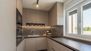 Eine moderne Küche mit integrierten Geräten, einem großen Fenster und einem minimalistischen Design.