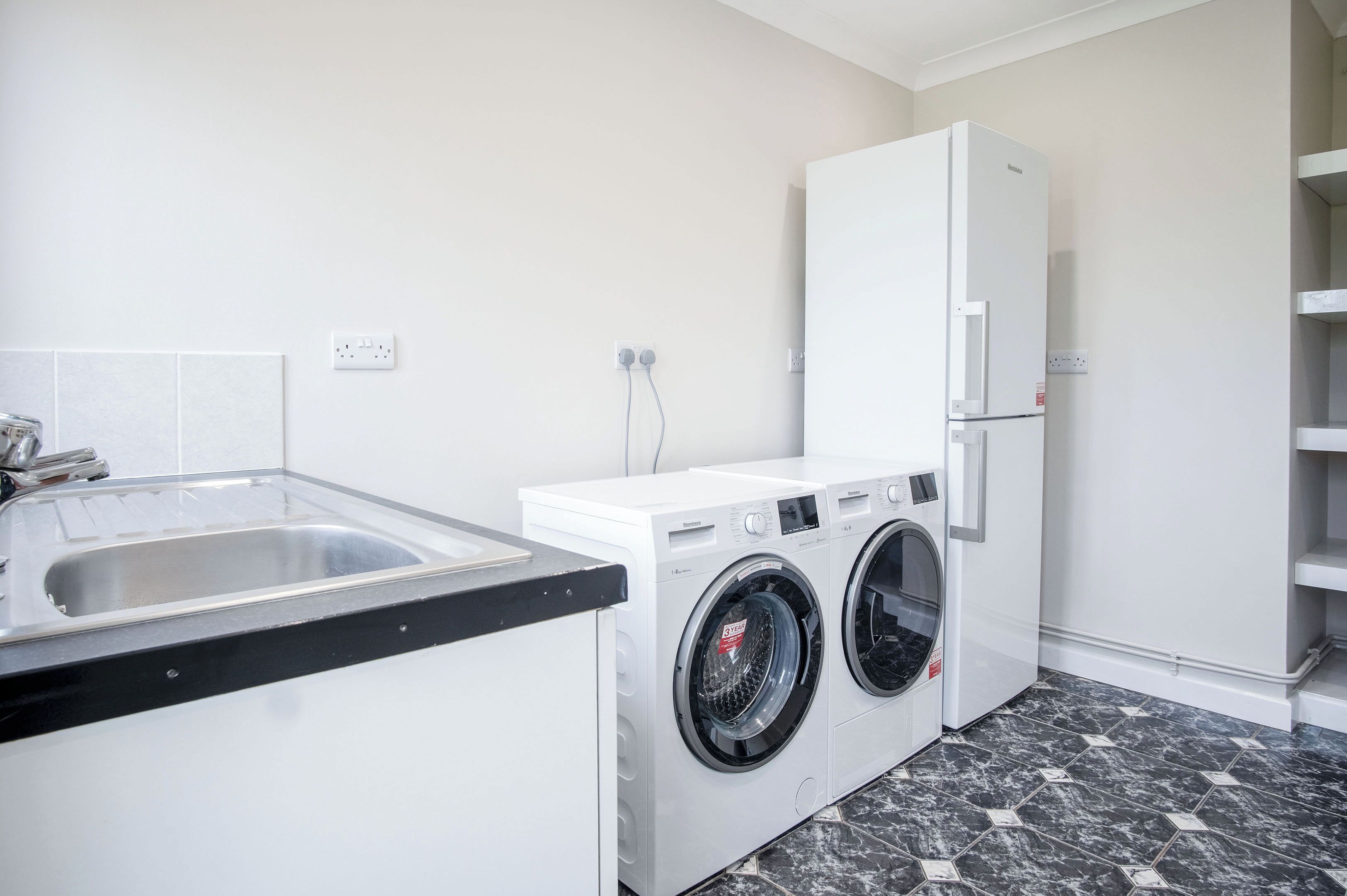 A compact laundry area with a washing machine, dryer, and a sink.