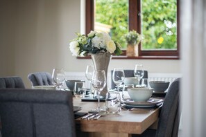 A dining table set with plates, bowls, and wine glasses, with a vase of flowers in the center. - Springfield Lodge - 3 Bedroom Home - Princes Gate (Narberth)