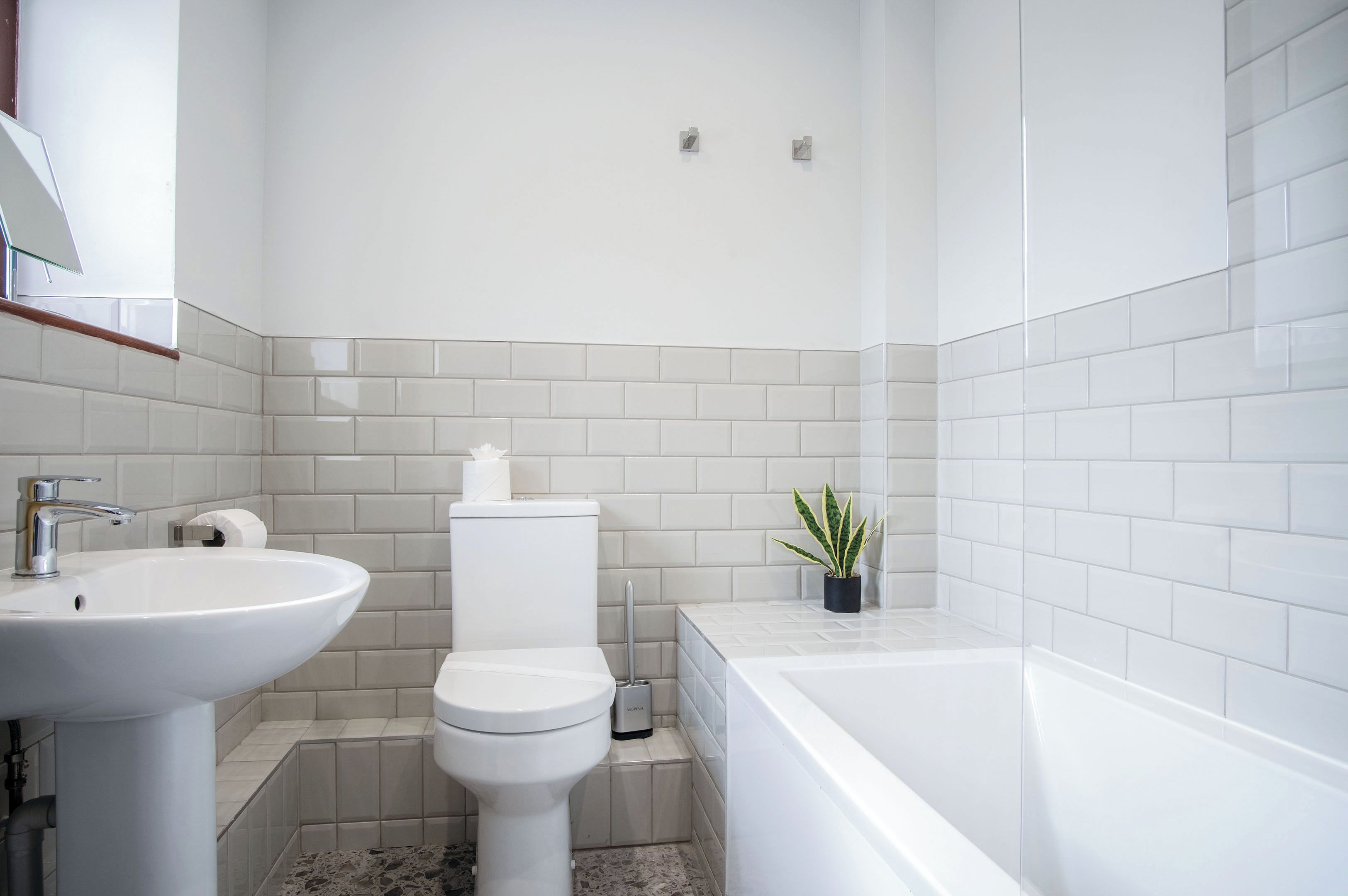Un baño moderno con lavamanos, inodoro y bañera blancos.