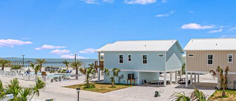 A coastal building with a pool, palm trees, and a clear blue sky.