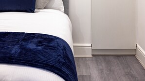 Ein Schlafzimmer mit einem Bett, einem Kleiderschrank und einem an der Wand hängenden abstrakten Kunstwerk.
