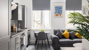 Eine moderne Küche mit grauen Schränken, einem Esstisch und einem grauen Sofa mit gelben Kissen.
