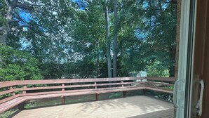 Une terrasse en bois avec une rambarde en métal, entourée d’arbres.