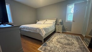 Une chambre à coucher avec un lit, des tables de chevet, un tapis et un téléviseur.