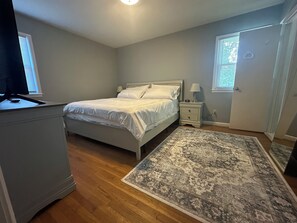 A bedroom with a bed, bedside tables, a rug, and a TV.