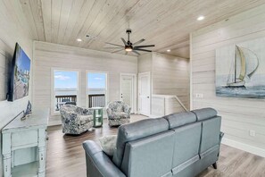 A spacious living area with a ceiling fan, a gray sofa, two patterned armchairs, a small table, and a painting of a sailboat. - 167 Seven Palms,  Set Sail Waterfront House: Pool, Hot Tub & Fishing! (Fulton)