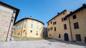 Ein Innenhof mit Steinpflasterung, Gebäuden mit Rundbogenöffnungen und blauem Himmel.