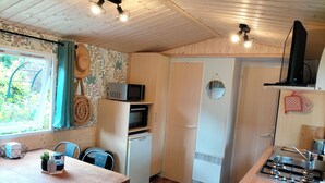 A compact kitchen with wooden cabinets, a microwave, a refrigerator, and a gas stove. - Cottage Cosy Aux Lauriers à Lacroix sur Meuse (Lacroix-sur-Meuse)