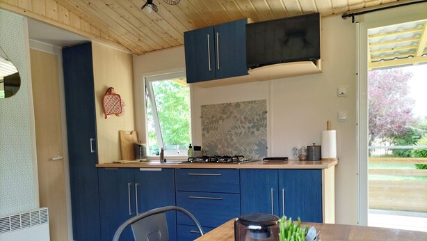 A modern kitchen with blue cabinets, a wooden table, and a coffee maker. - Cottage Cosy Aux Lauriers à Lacroix sur Meuse (Lacroix-sur-Meuse)