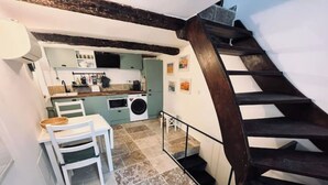 Une cuisine équipée d’un lave-linge, un coin repas avec une table et des chaises, et un escalier avec des marches en bois foncé.