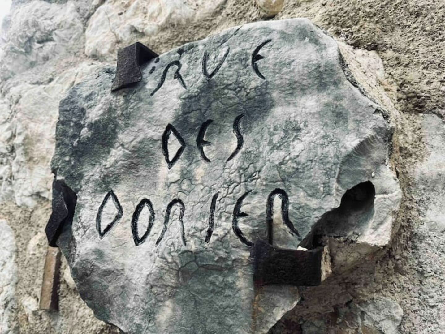 Une pierre portant des inscriptions, entourée d’un terrain accidenté.