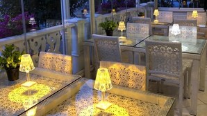 Un espace extérieur aménagé en terrasse, avec des tables et des chaises, chacune étant dotée d’une lampe de table.