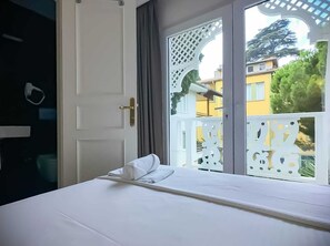 A hotel room with a bed, a window with a decorative white lattice, and a view of buildings and trees outside. - hi Hotel Ivy Buyukada (Adalar)