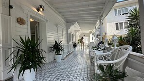 A covered corridor with white railings, potted plants, and a tiled floor. - hi Hotel Ivy Buyukada (Adalar)