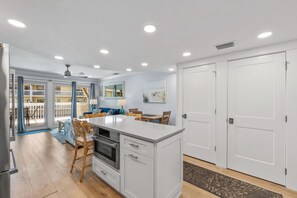 A modern kitchen with a central island, built-in appliances, and a dining area with chairs and a table.