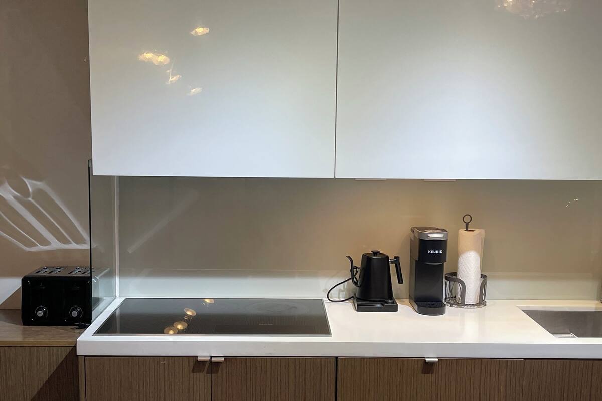 A kitchen with a white countertop, a coffee maker, a Keurig coffee maker, and a toaster.