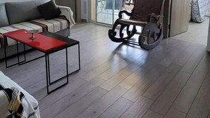 En moderne stue med en sofa, et rødt sofabord og en anderledes gyngestol.