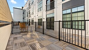A modern building with a wooden deck and black metal railing.