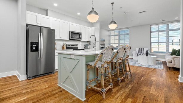 A modern kitchen with white cabinets, stainless steel appliances, and a central island.