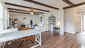 Un salón espacioso con un sofá blanco, una mesa de comedor y un ventilador de techo.