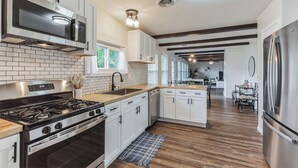 Una cocina moderna con armarios blancos, estufa de acero inoxidable y un refrigerador grande.
