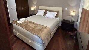 A modern bedroom with a large bed, a bedside table, a nightstand, and an air conditioning unit. - 2stay - Luxury (Ponta Delgada)