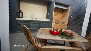 A barbecue area with a table and chairs, a sink, and a tiled backsplash. - 2stay - Luxury (Ponta Delgada)