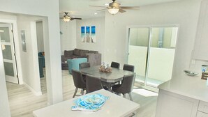 A modern kitchen with a white countertop, a dining area with a table and chairs, and a ceiling fan. - New Beach & Bay Retreat Full of Amenities! (Long Beach)