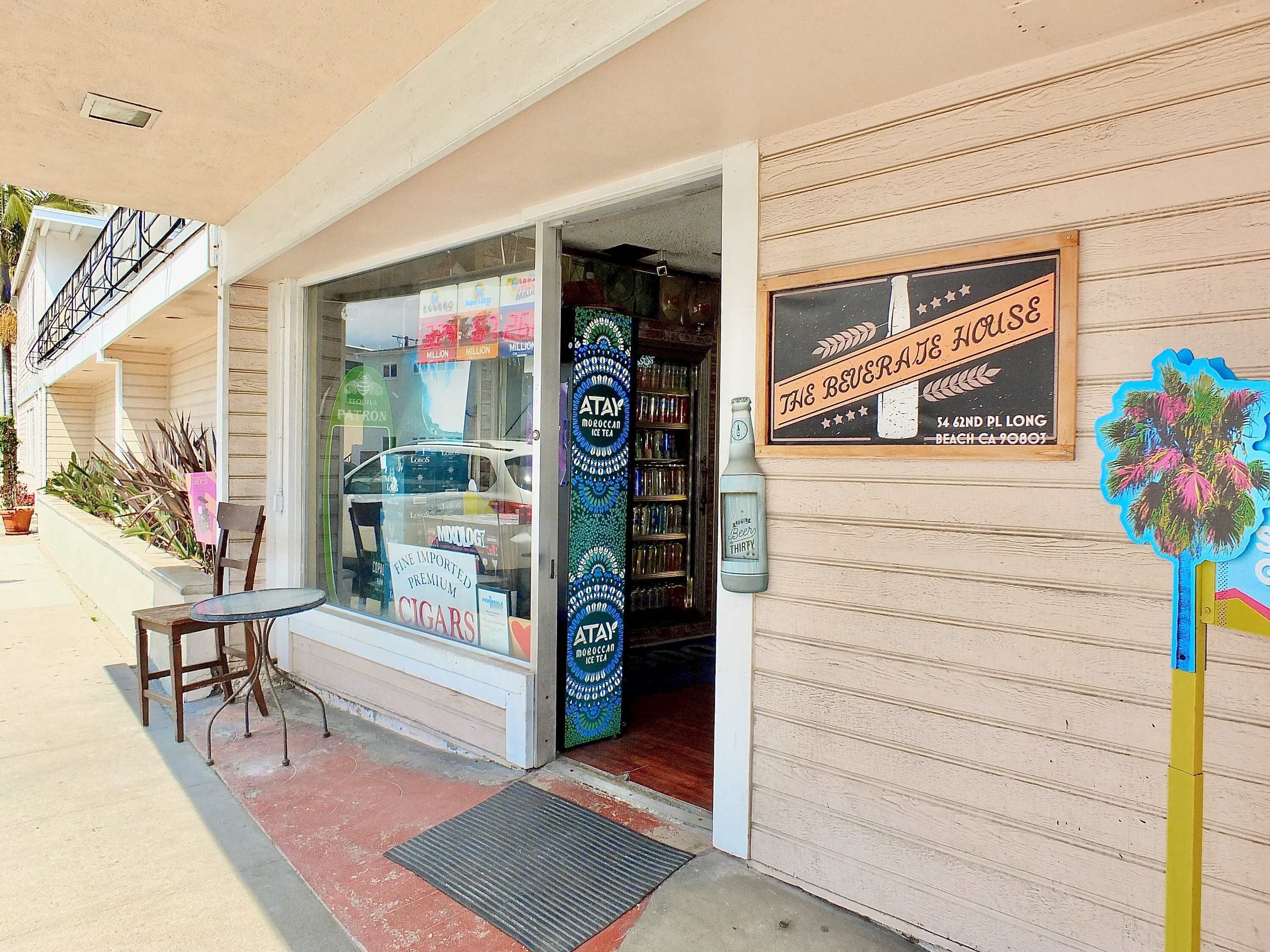 A storefront with a glass door, a sign for 'The Beverage House', and a display of beer bottles.