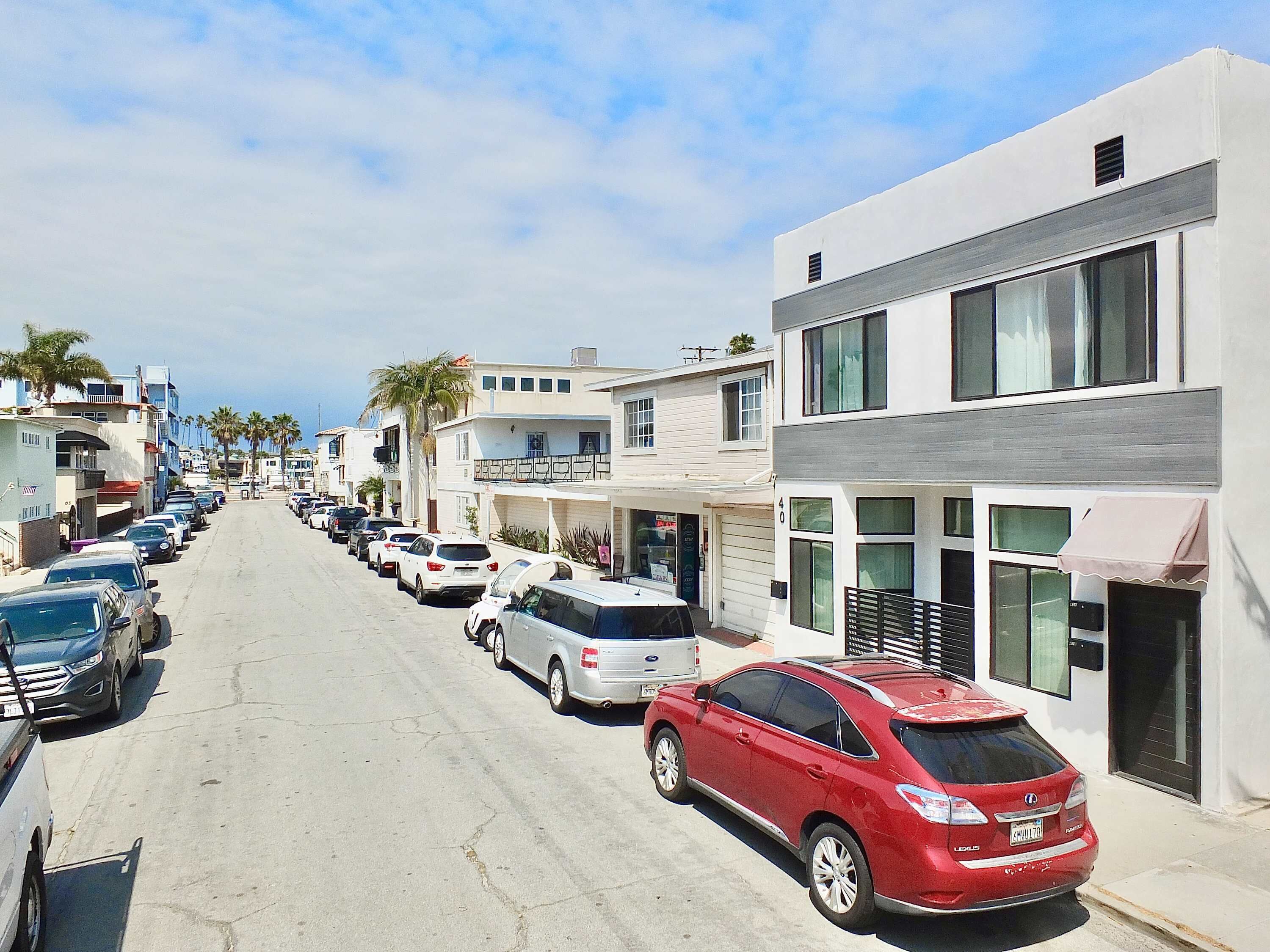 A street lined with parked cars and buildings with balconies.
