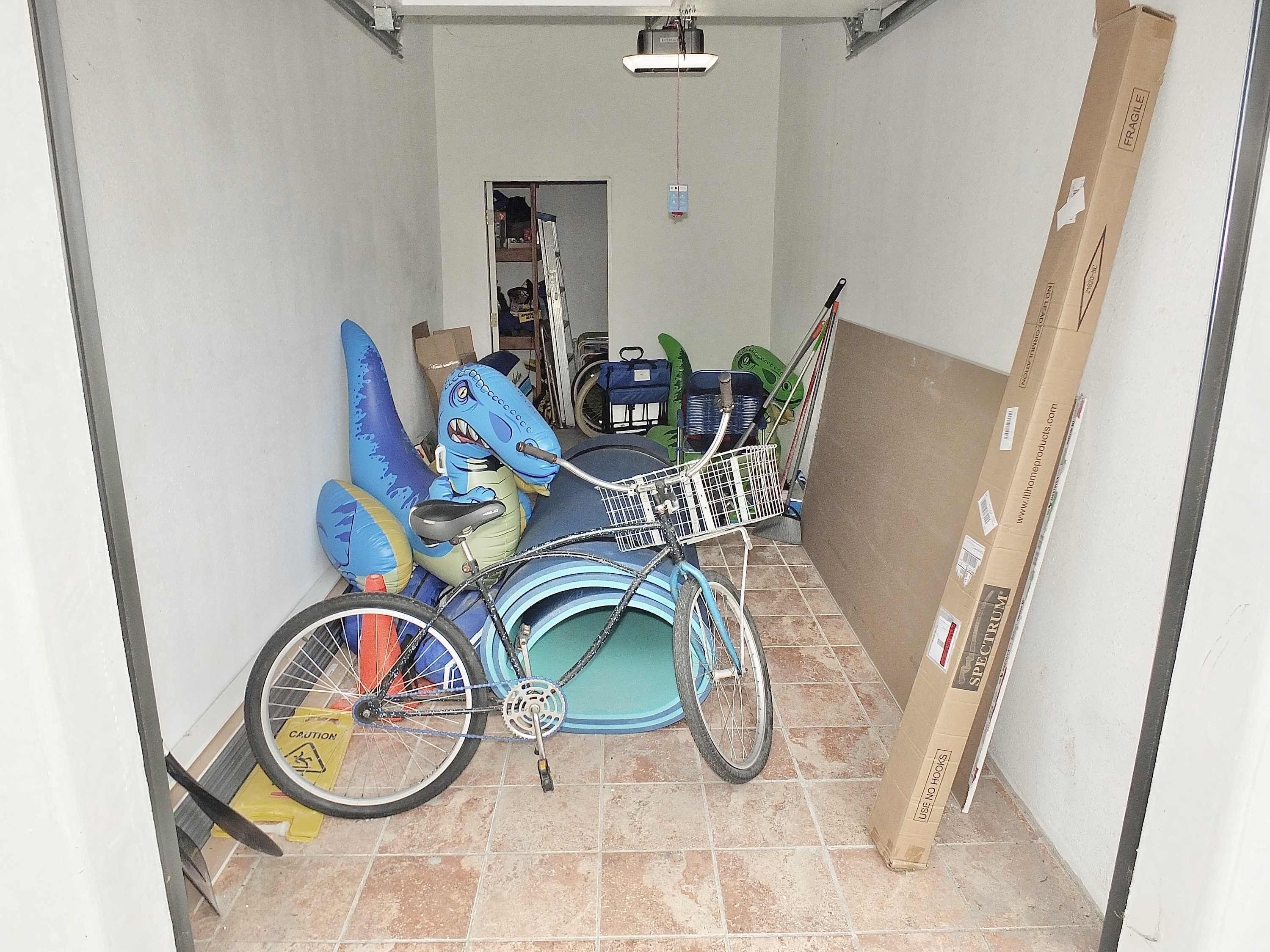 Un pasillo estrecho con una bicicleta, juguetes inflables y cajas de cartón.