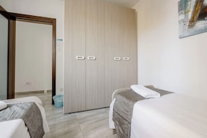 Ein Hotelzimmer mit zwei Betten, einem Kleiderschrank und einem Mülleimer.