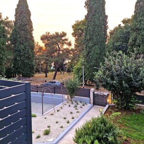 Seating areas line the paved walkway, surrounded by lush vegetation and trees.