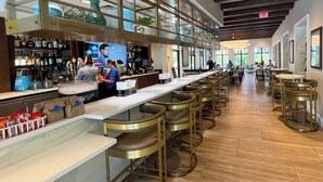 A bar area with a long counter, stools, and a variety of bottles on shelves. - Always Summer on Sunshine Ridge (Kissimmee)