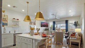 A modern kitchen with white cabinets, a central island, pendant lighting, and a dining area with a chair and table. - New Listing Be Our Guest in Utah (Washington)