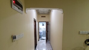 A hallway with a tiled floor, a ceiling with decorative patterns, and a door leading to another room. - A Stunning, Newly Built 3-bedroom Property to Rent (Iyakachchi)