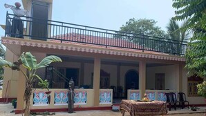 A two-story building with a balcony, a covered porch, and a table with chairs outside. - A Stunning, Newly Built 3-bedroom Property to Rent (Iyakachchi)