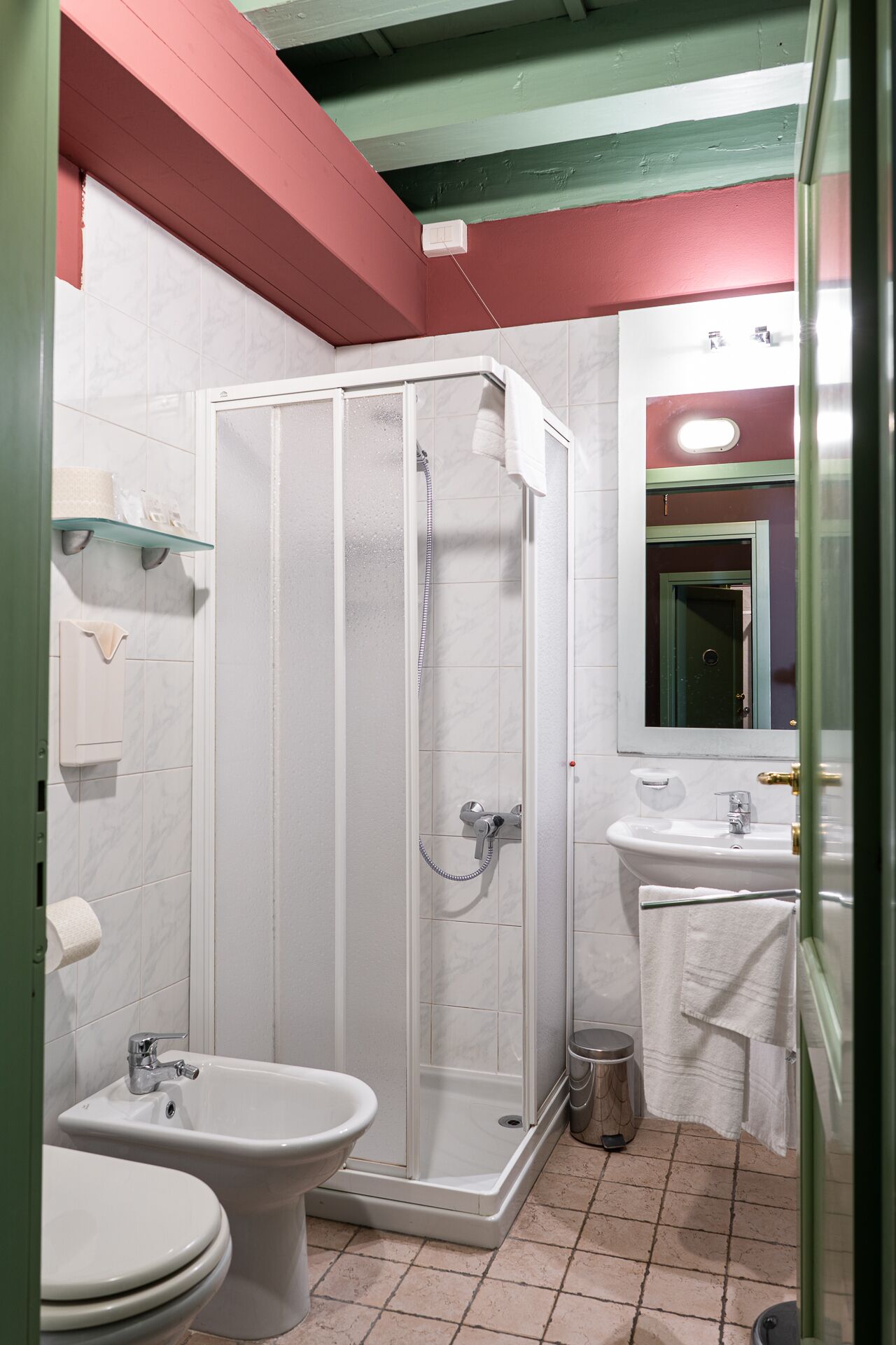 A bathroom with a shower, bidet, sink, and toilet.