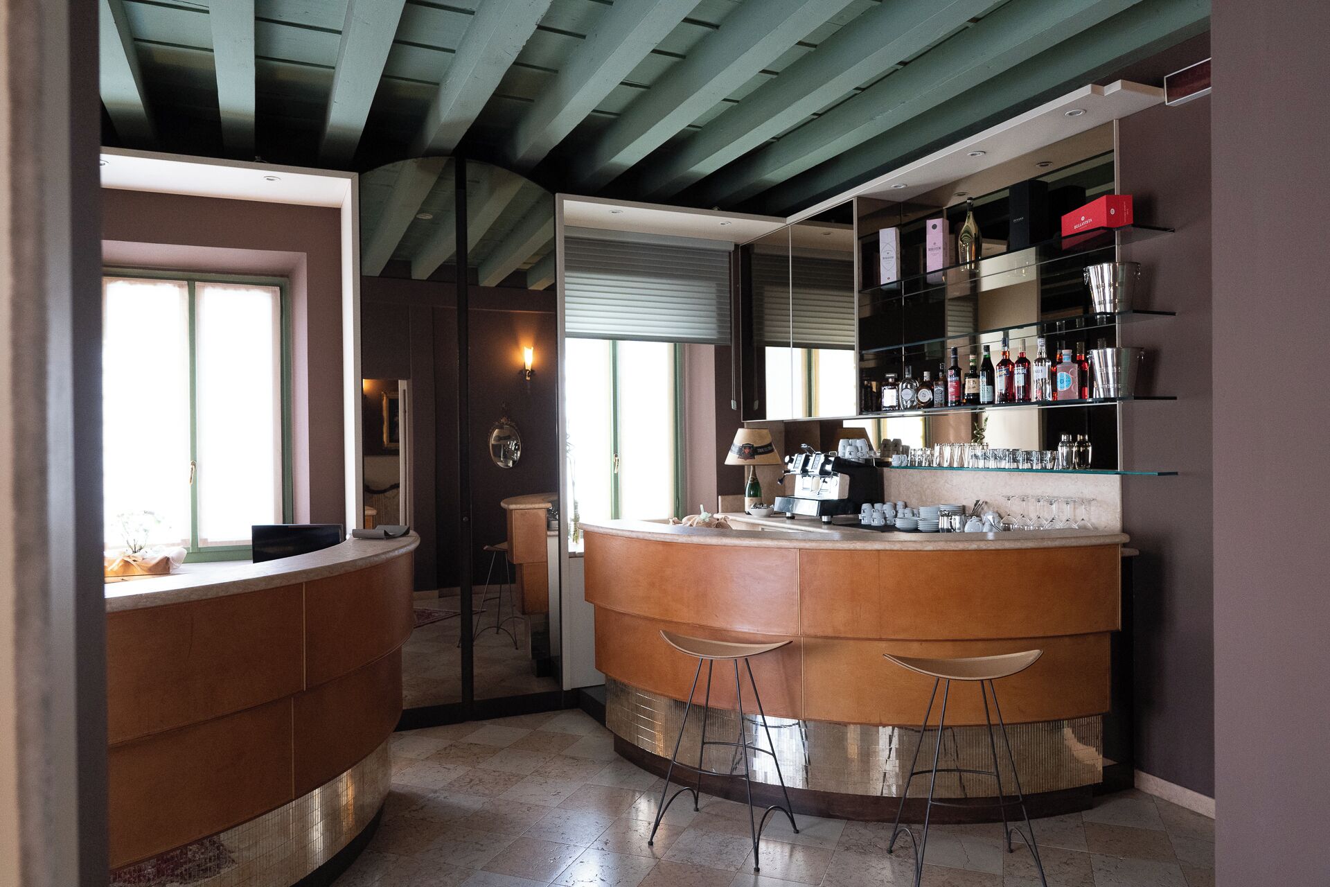 Een bar met een gebogen toonbank, krukken en gevulde planken met flessen en glazen.