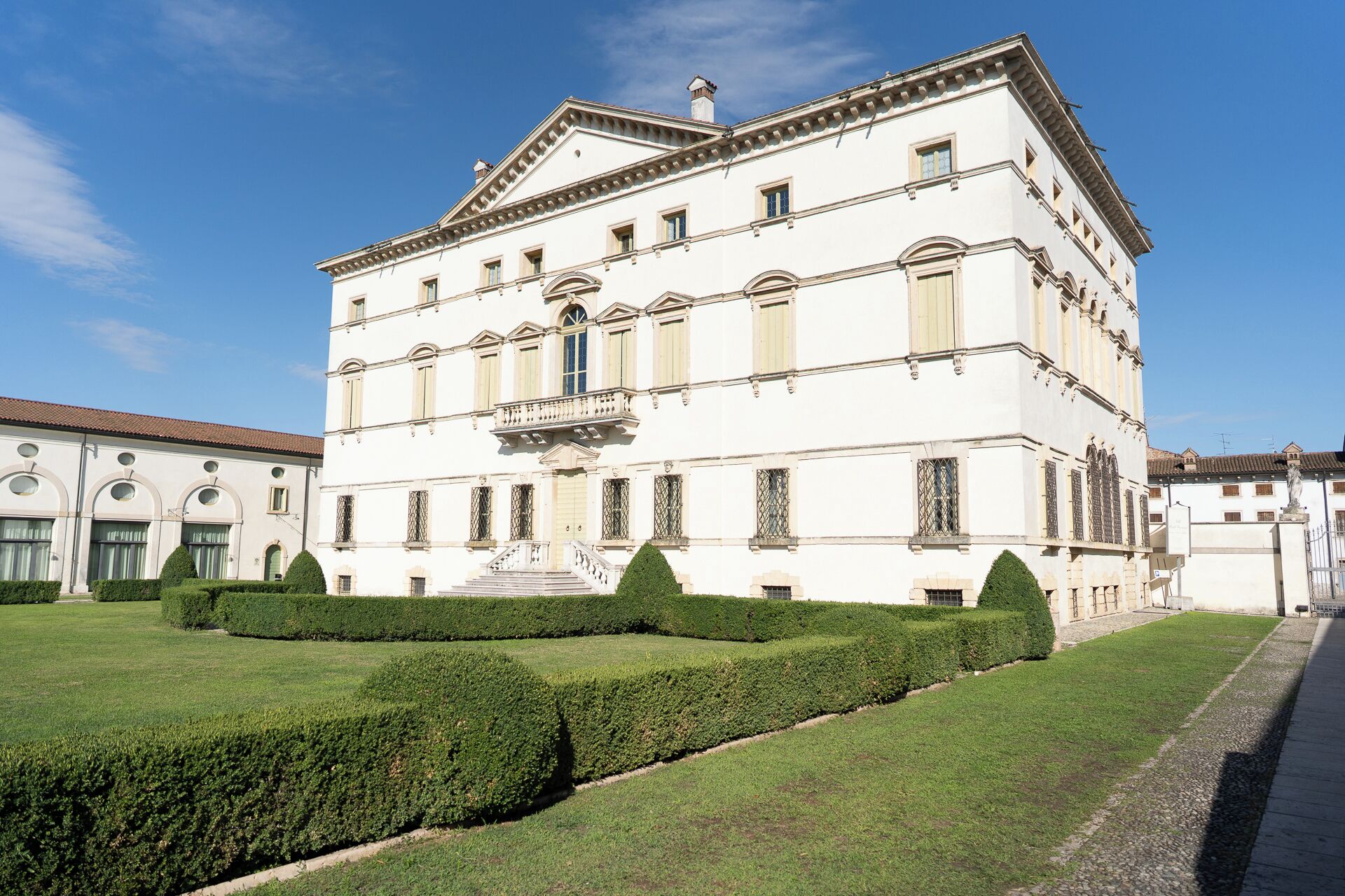 A large, white building with a symmetrical facade, multiple windows, and a central staircase leading to an upper floor.