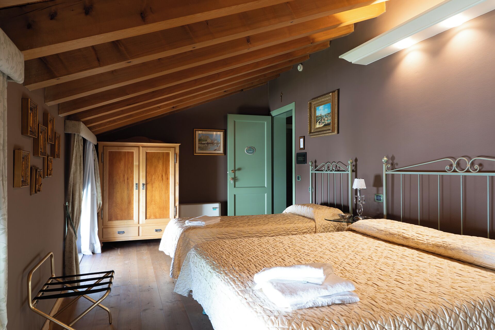 A bedroom with two beds, a wooden ceiling, a green door, and a metal headboard.