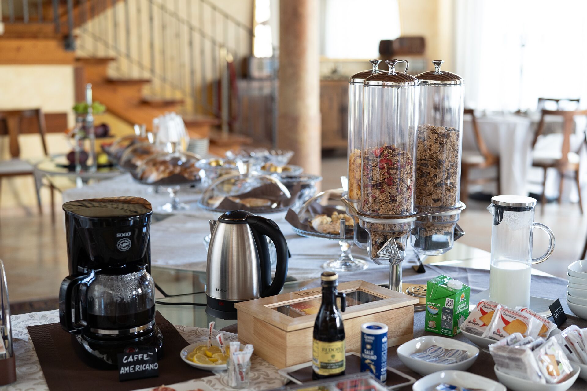 Ein reichhaltiges Frühstücksbuffet mit verschiedenen Speisen, einer Kaffeemaschine und einem Milchkännchen.