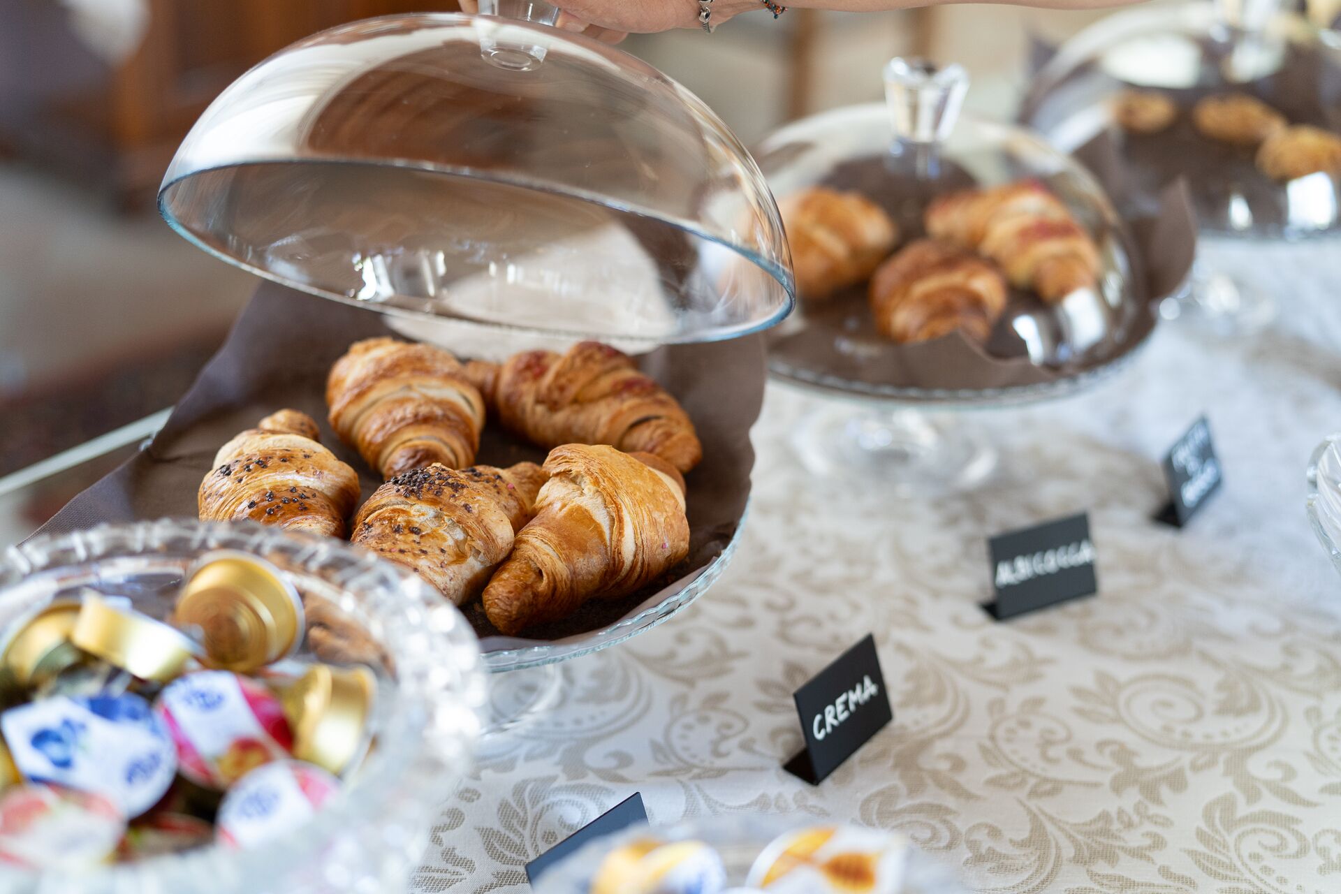 Ett buffébord med ett urval av bakverk, inklusive croissanter och andra småbröd, som presenteras i glasskålar.